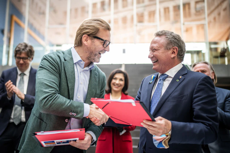 Two happy men in suits shake hands.