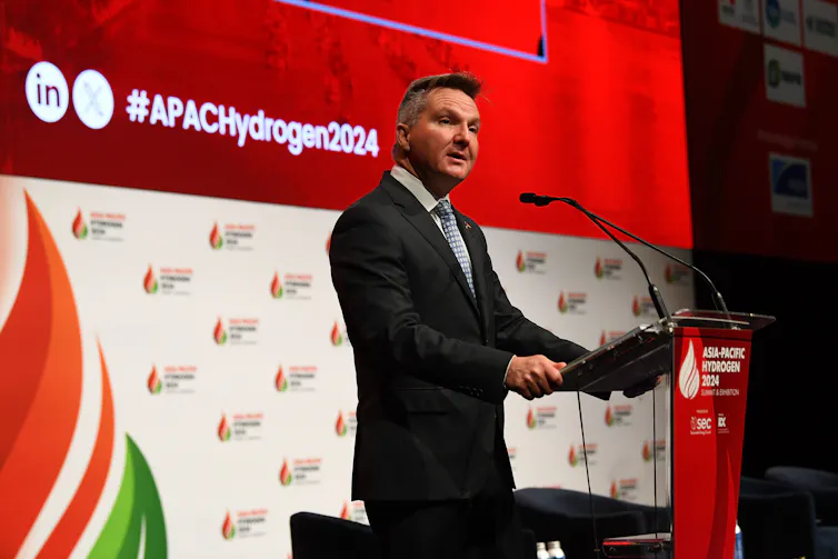 A man in a suit stands at a lectern
