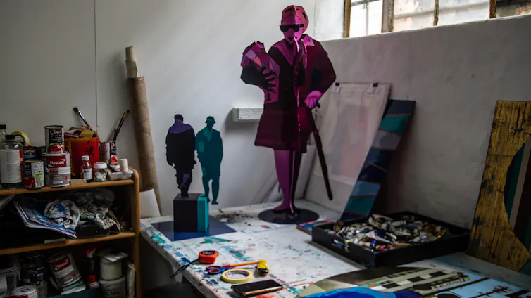 A studio with drawings and painting materials, a sculpture on a table of a woman smartly dressed.