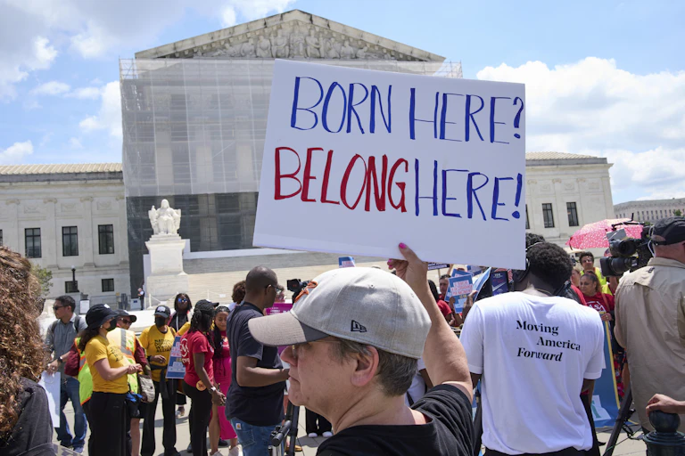 A person holds a sign in front of a federal building.