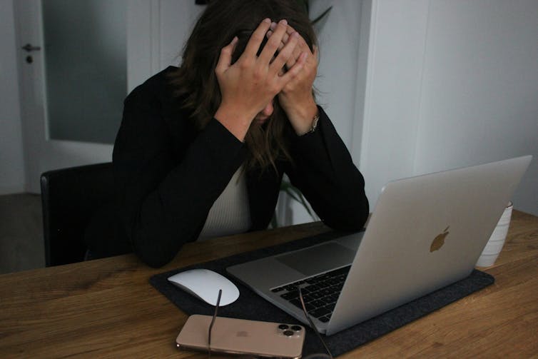 A woman sits in an office with her head in her hands