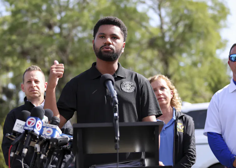 A Black man gestures as he addresses an outdoor news conference.
