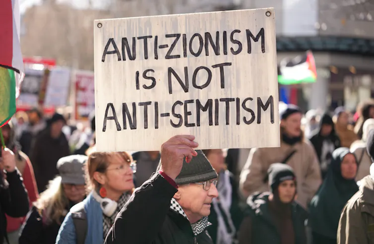 Pro-Palestine protestor holding up a sign that reads 'Anti-zionism is not anti-semitism'.