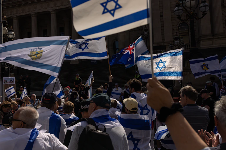Several Israeli flags being flown at a protest