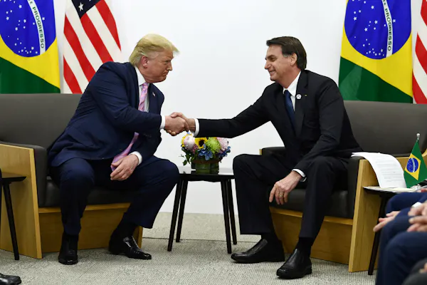 Two men in suits shake hands.