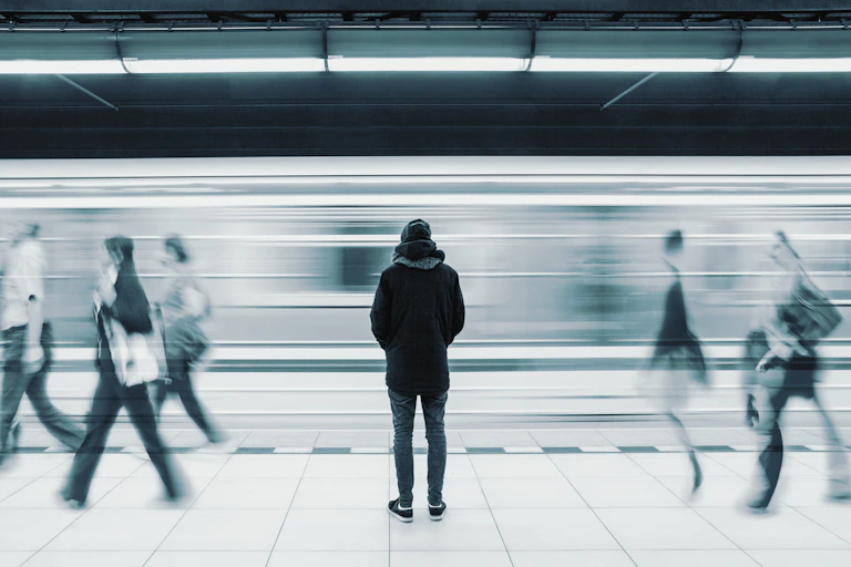 Un joven aislado en un andén del metro. Foto en blanco y negro.