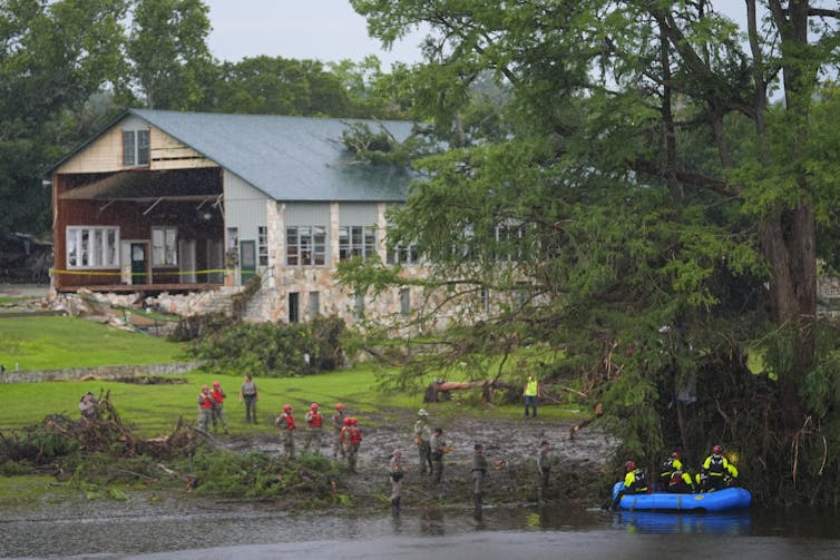 Rescue workers are seen on land and on a boat as they search for missing people near Camp Mystic along the Guadalupe River after a flash flood swept through the area Sunday, July 6, 2025, in Hunt, Texas.