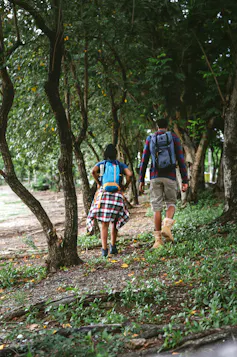 two people walk through a forest
