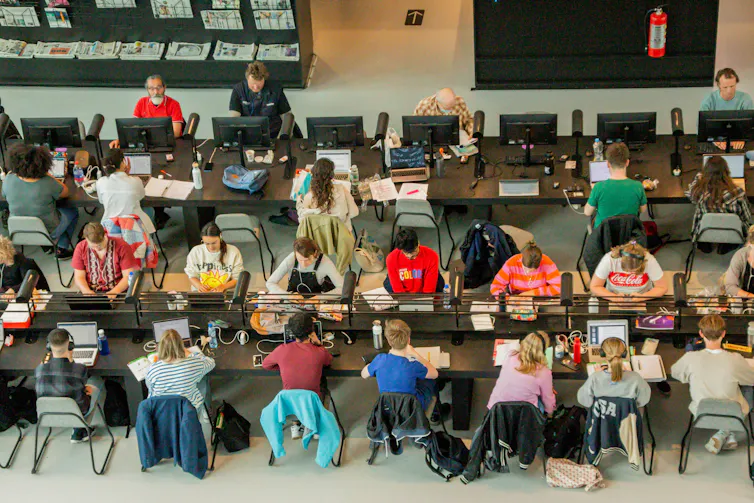 Students working in college library with laptops.