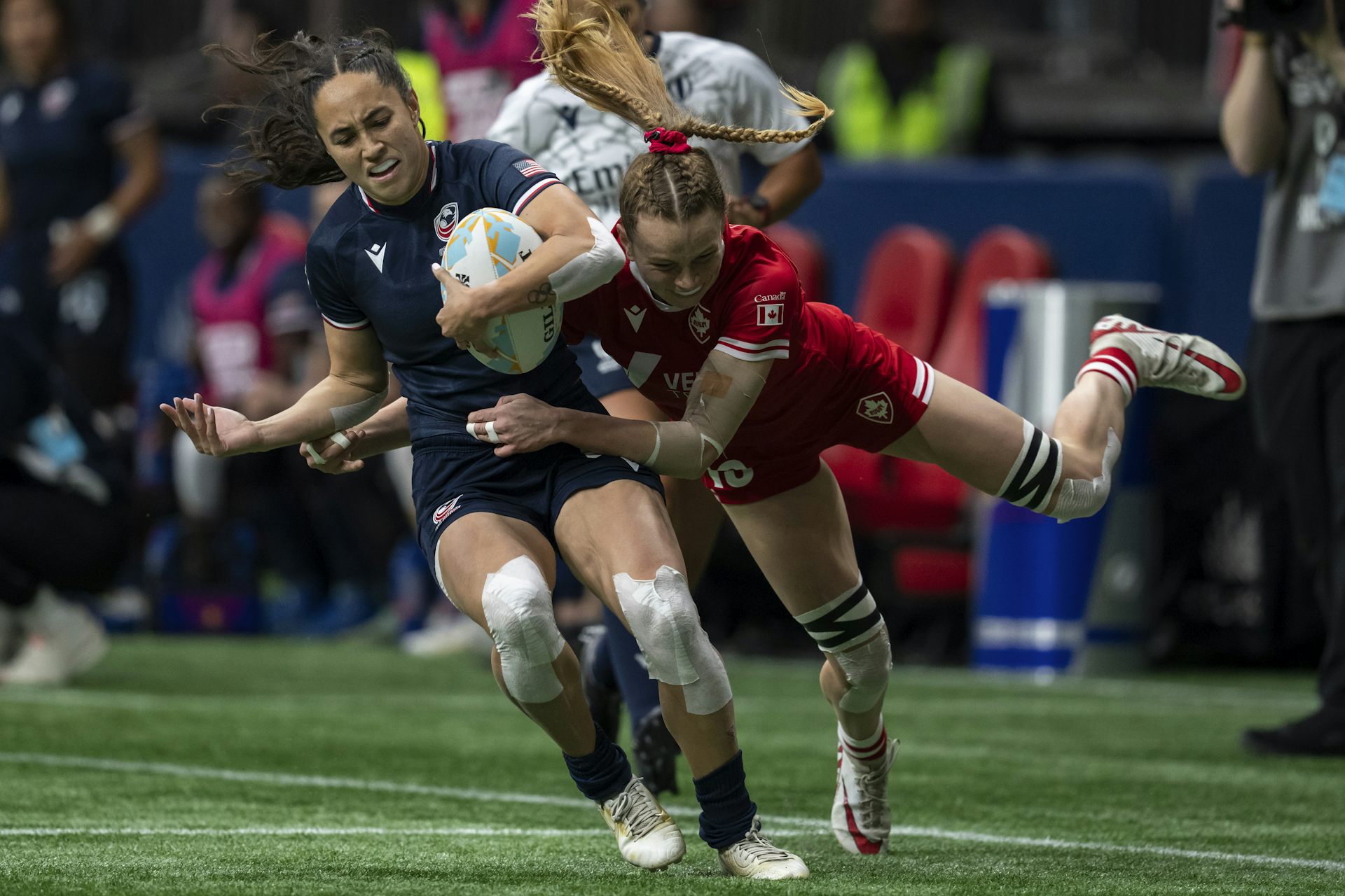 La mujer en el rugby rojo en uniformes trata con otra mujer en la Marina en la Marina en el tono de rugby