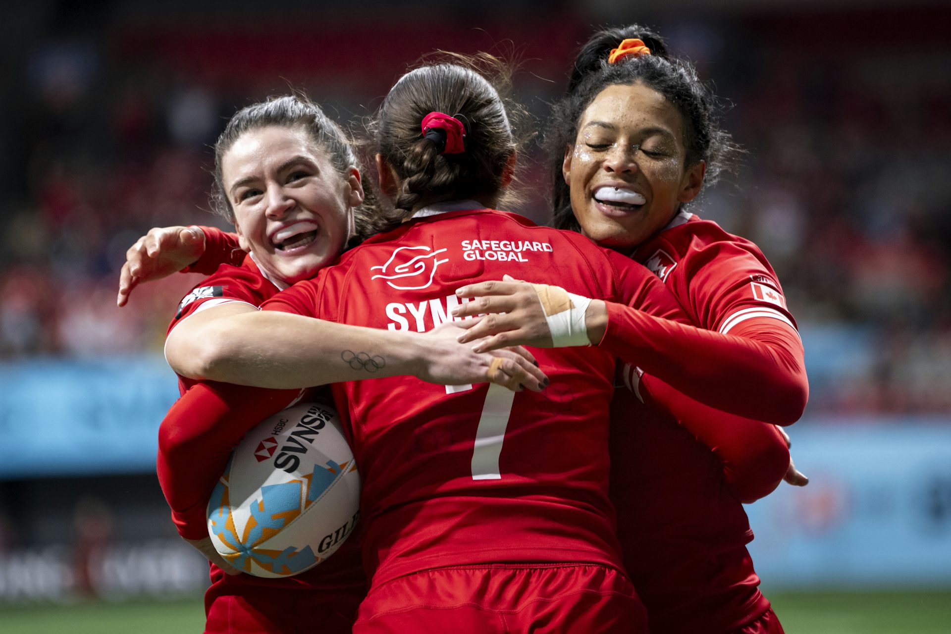 Se aceptan tres mujeres con uniformes de rugby rojos en el rugby