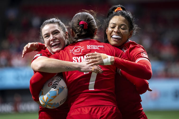 Se aceptan tres mujeres con uniformes de rugby rojos en el rugby