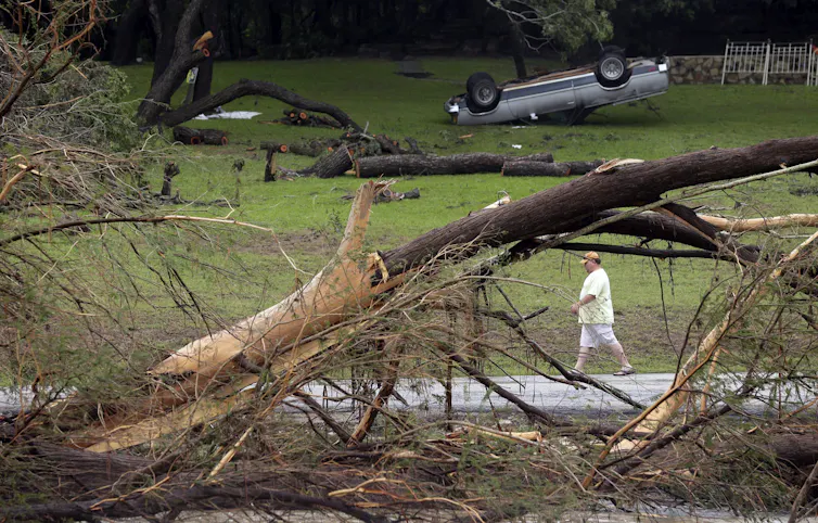 a man walks past an upturned car