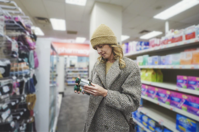 Woman compares vitamins at the supermarket