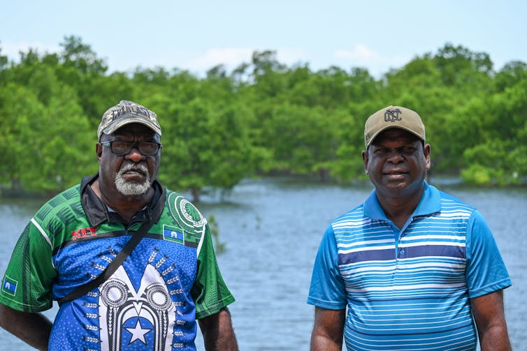 Paul Kabai and Pabai Pabai stand facing the camera with a swamp in the background at Boigu Island in the Torres Strait Islands.