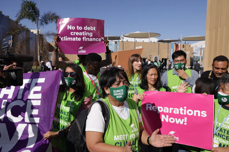 People wearing green vests and masks and carrying posters