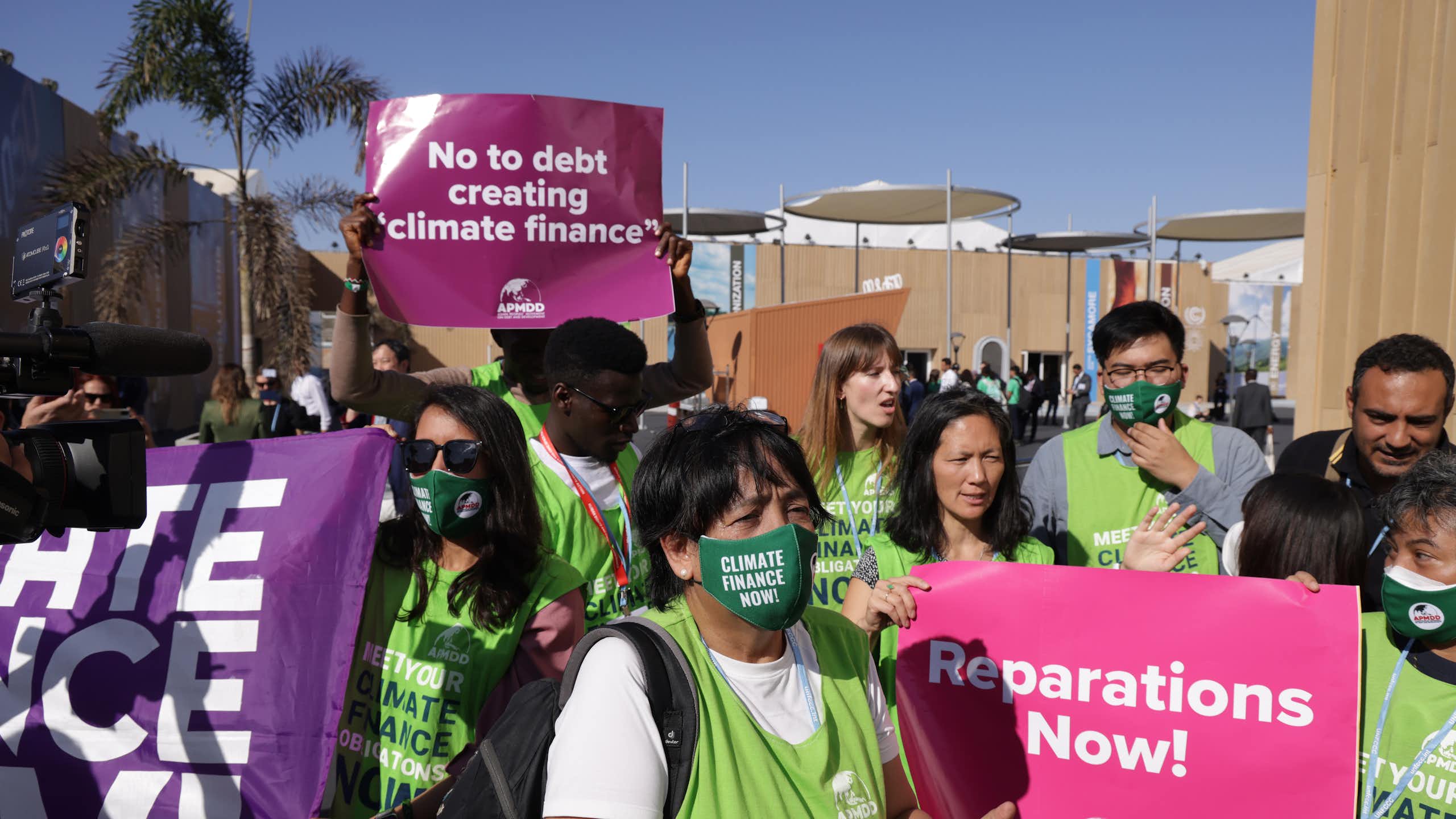 People wearing green vests and masks and carrying posters