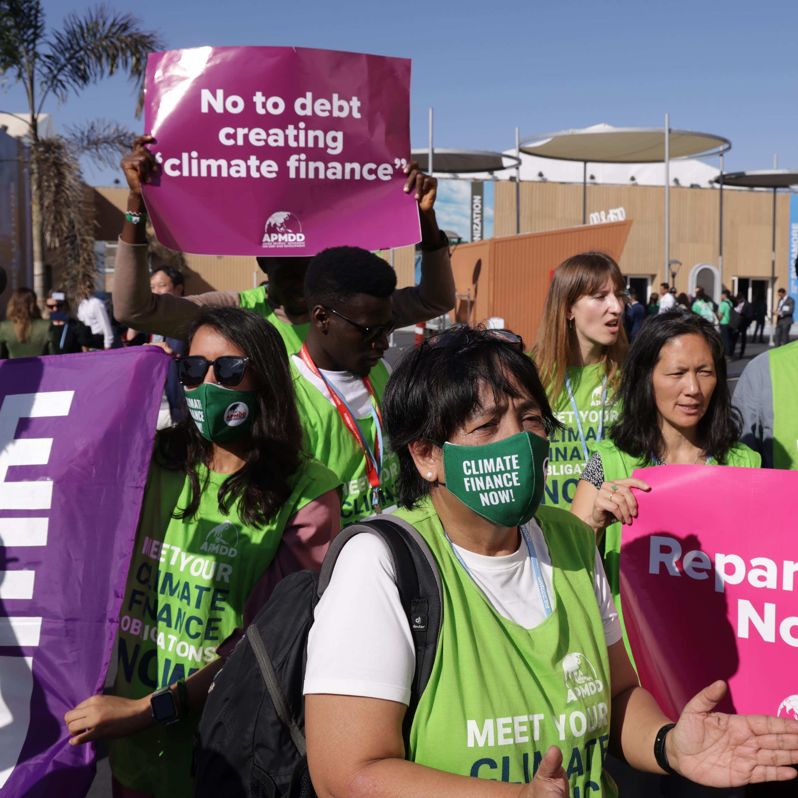 People wearing green vests and masks and carrying posters
