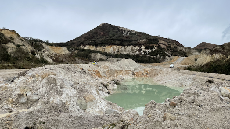 quarry pit, mound in background, blue sky