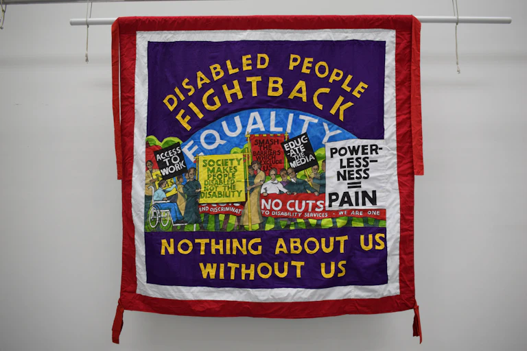A hand-stitched banner in support of disabled people's rights
