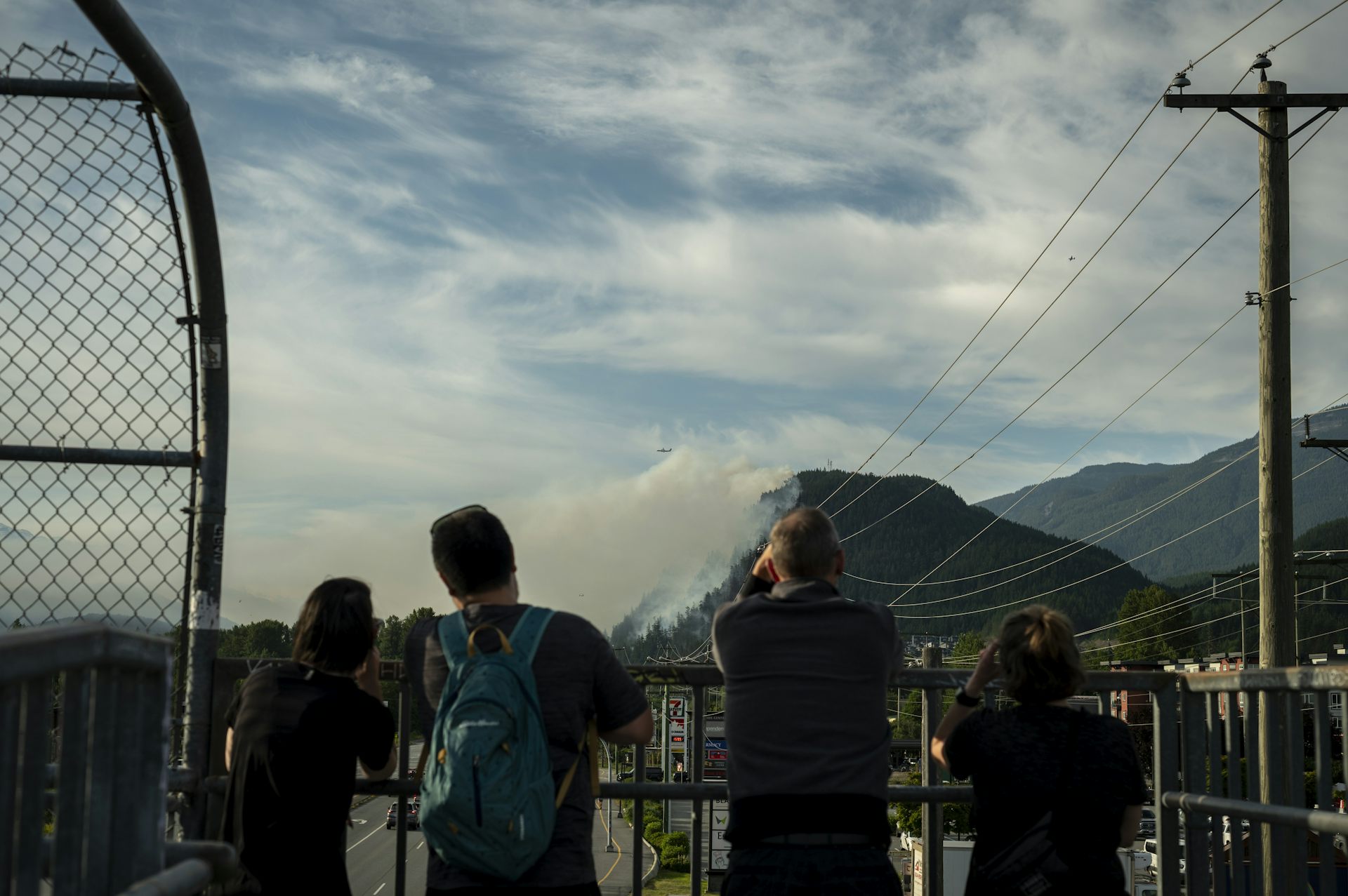 Gente vista al ver una lluvia de humo blanco que se eleva al lado de una montaña cubierta de madera