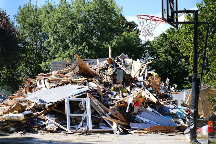 A pile of wood and rubble sits next to a basketball hoop.