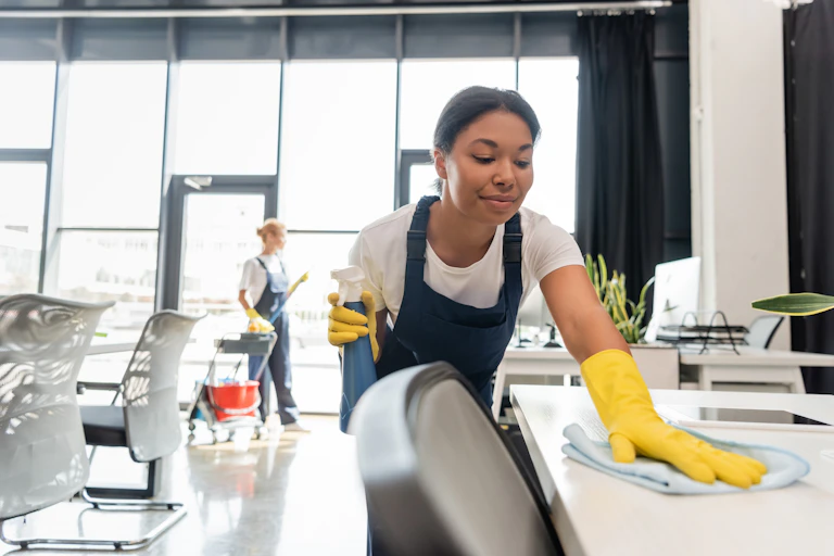 Young woman cleaner wiping down a desk