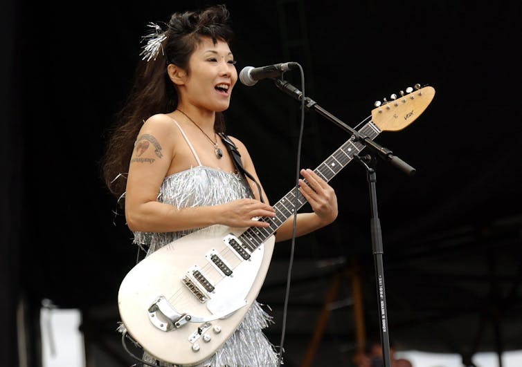 A Japanese woman with a white electric guitar.