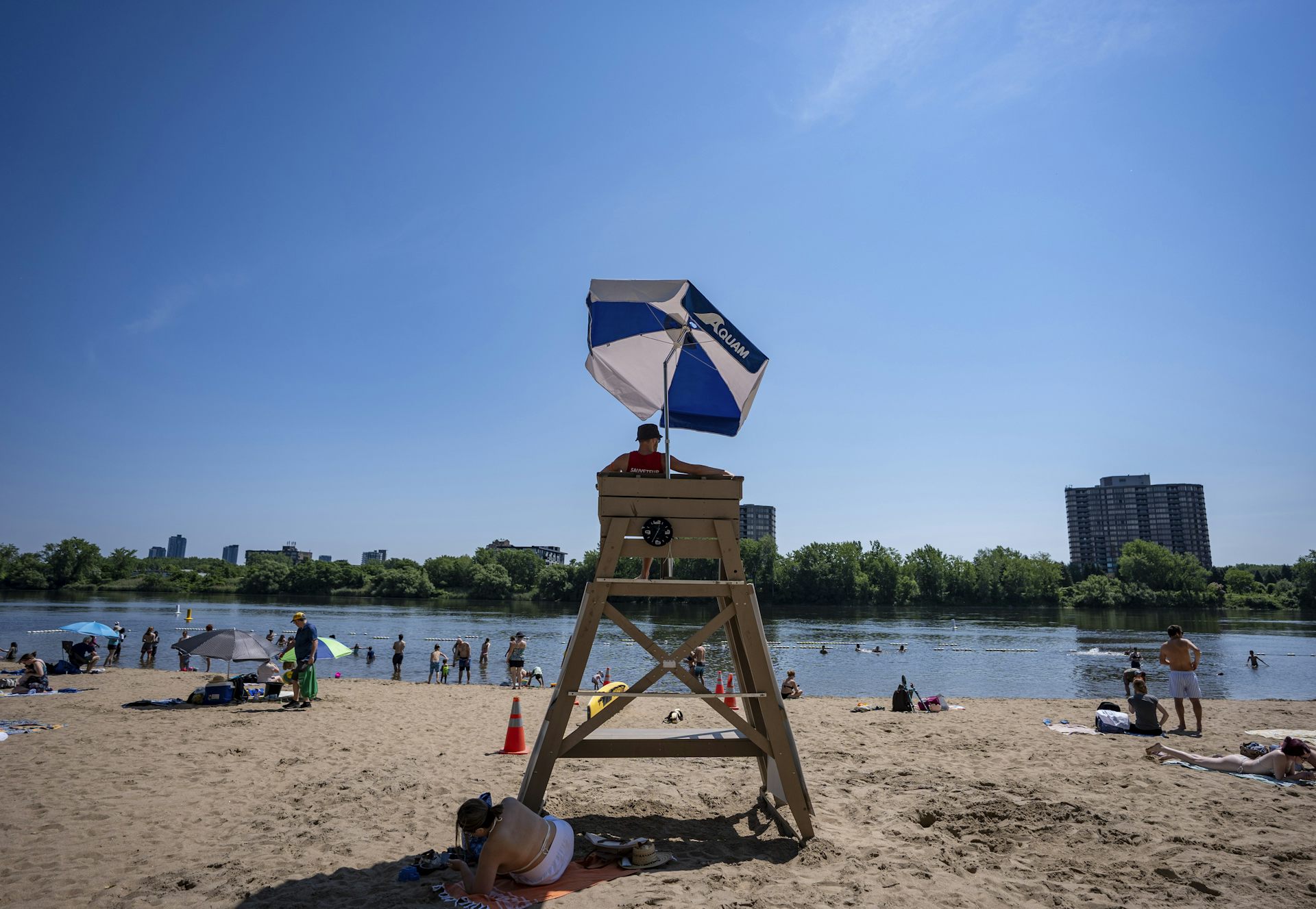 A sandy beach with a lifeguard tower and a blue and white sun umbrella
