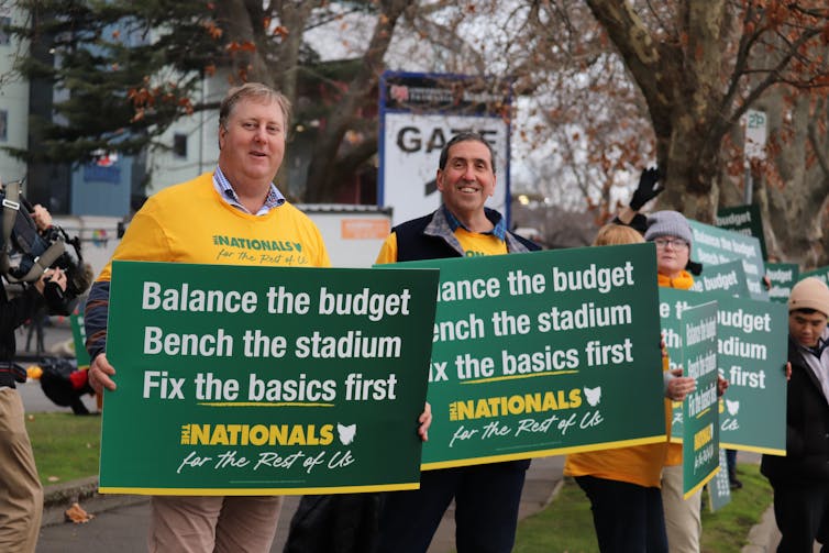 A row of people holding up signs in green and yellow.