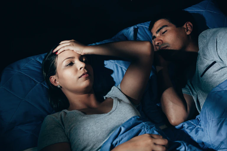 Woman awake in bed in middle of night, male partner sleeping