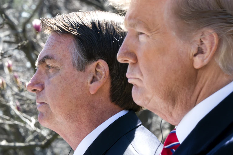 Two men in suits stand next to each other.