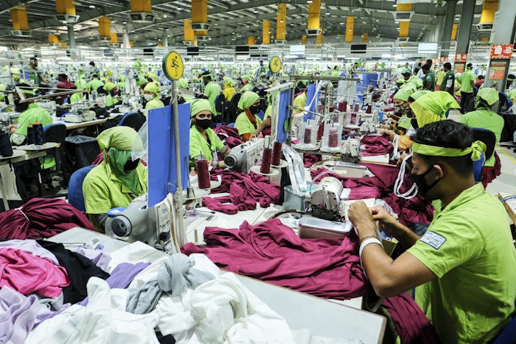 Workers stitch garments at a factory.