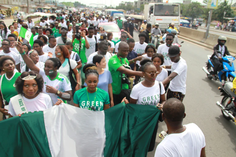 Marchers in green and white hold up the Nigerian flag.
