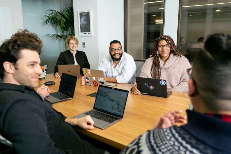People sitting around a table with laptops.