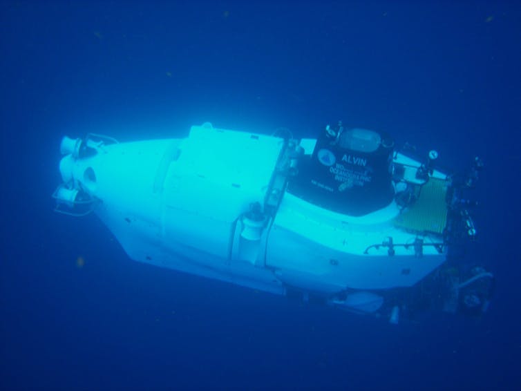 A small, cylindrical capsule with equipment attached to the top travels underwater.