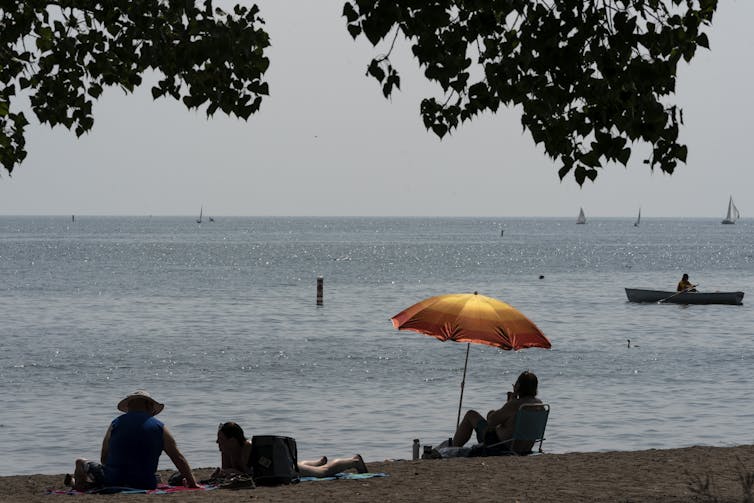 Gente en la playa en un día nublado con subsidiarias en primer plano.