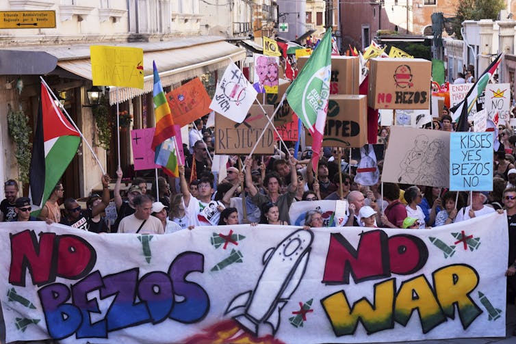 Un montón de protestas sosteniendo banderas, letreros y banquias diciendo que