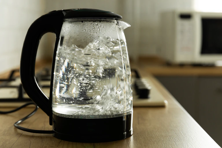 Modern electric transparent kettle on a wooden table in the kitchen.