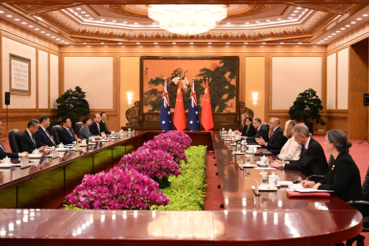 Anthony Albanese and Xi Jinping sitting opposite each other at a long table in the Great Hall of the People.