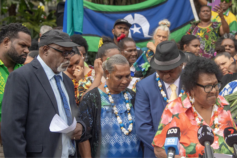 People from the Torres Strait gather in front of a flag