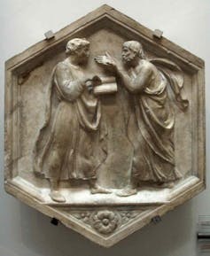 A small relief depicts two men in robes gesturing while they speak animatedly with each other.