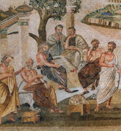 A close-up of a mosaic shows several men talking and sitting in a semicircle outside, wearing robes.