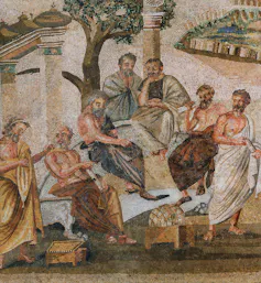 A close-up of a mosaic shows several men talking and sitting in a semicircle outside, wearing robes.