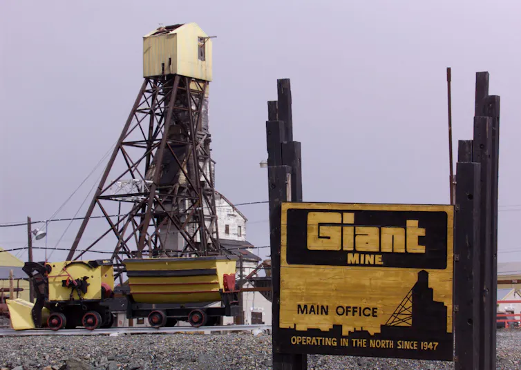 the headframe of a mine behind a sign reading Giant Mine.