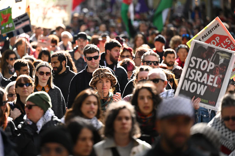 Protestors with a banner that reads 'Stop Israel Now'