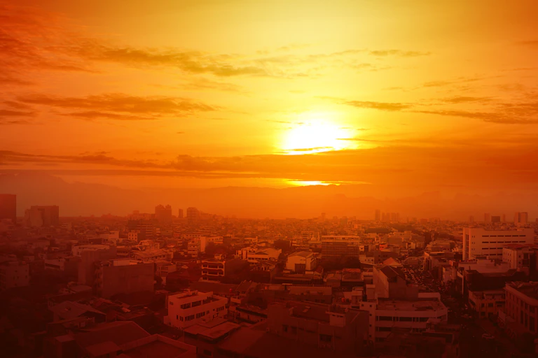 Un sol intenso en un cielo naranja sobre una ciudad