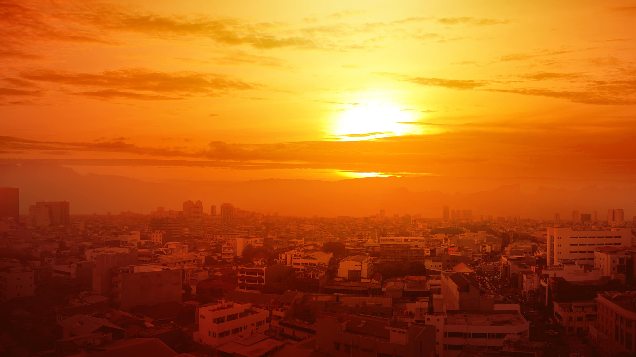 Un sol intenso en un cielo naranja sobre una ciudad