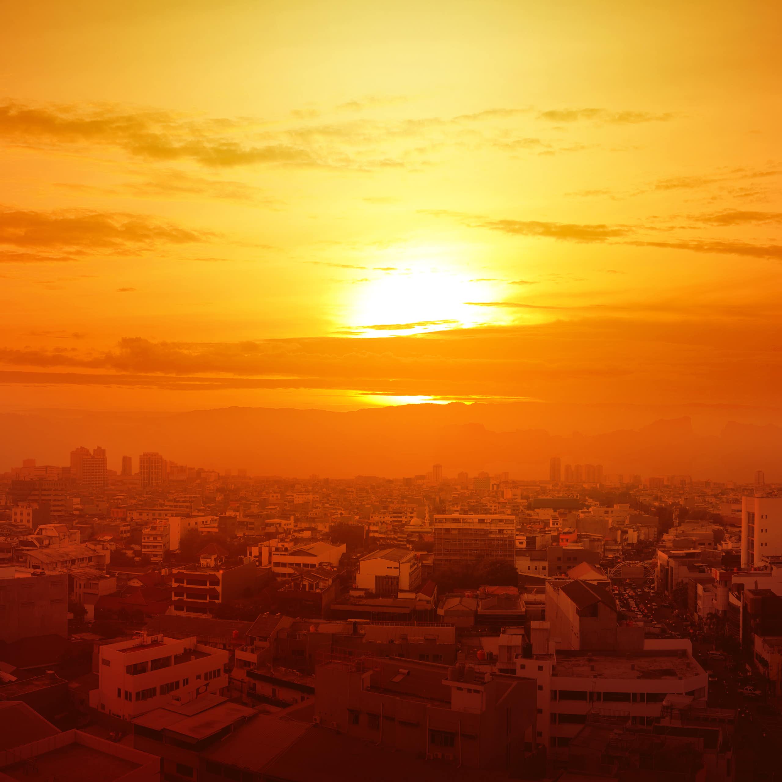 Un sol intenso en un cielo naranja sobre una ciudad