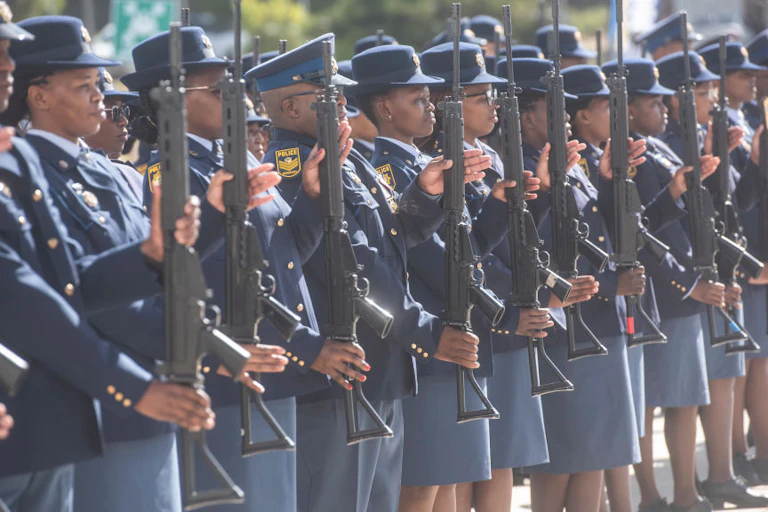Row of women and men in blue uniforms, holding rifles upright